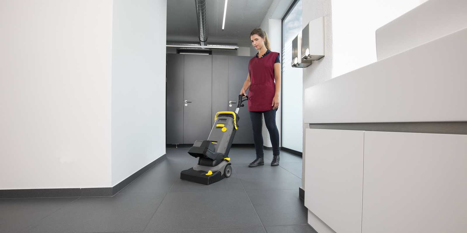 Sanitärreinigung Eine Person bedient einen Elektrobesen in einer Sanitäranlage