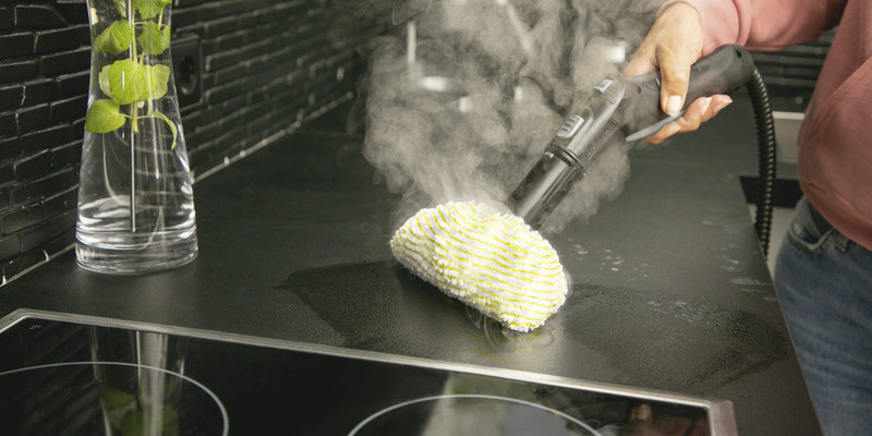 Person cleaning kitchen with steam cleaner