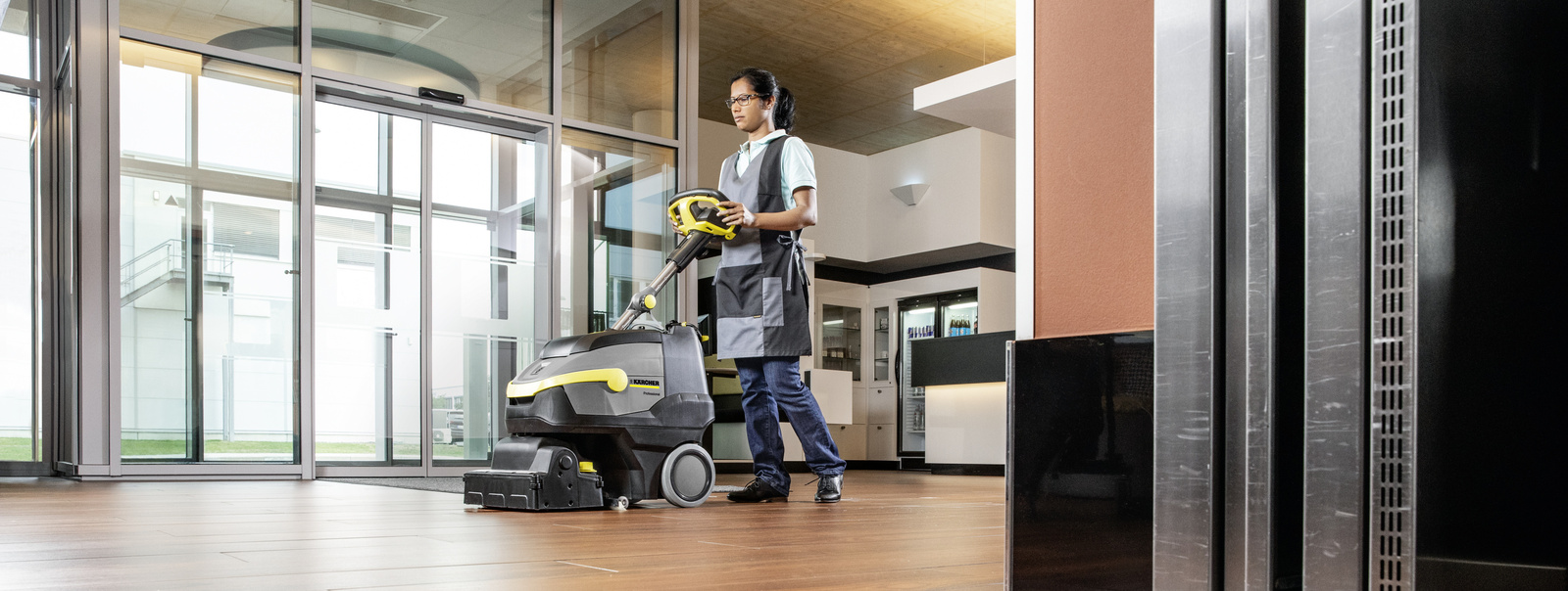 Scrubber dryer A person operating a Kärcher scrubber dryer on wooden floor