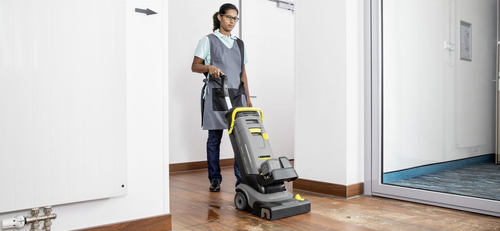 Scrubber dryer in use A woman maintaining a wooden floor with a scrubber dryer