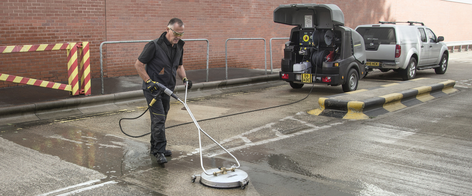 Hochdruckreiniger für Asphalt Eine Person reinigt eine Straße mit einem Hochdruckreiniger von Kärcher
