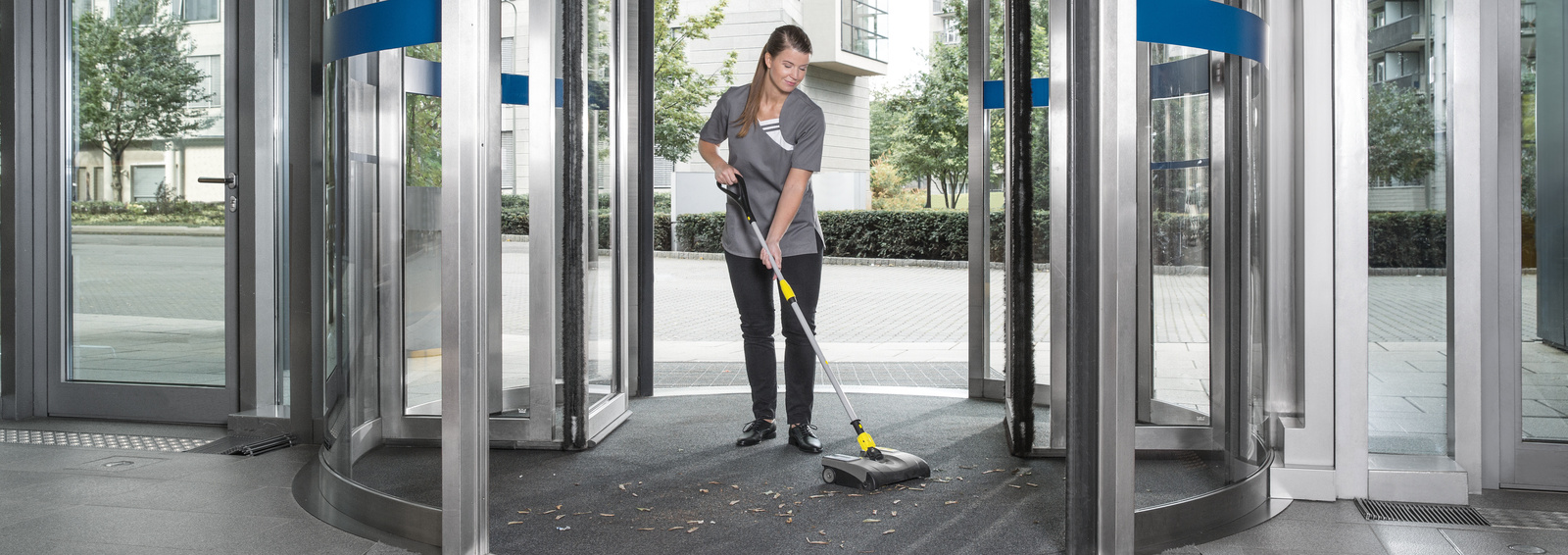 Electric broom in entrance area A person cleaning the floor in a revolving door with a Kärcher electric broom