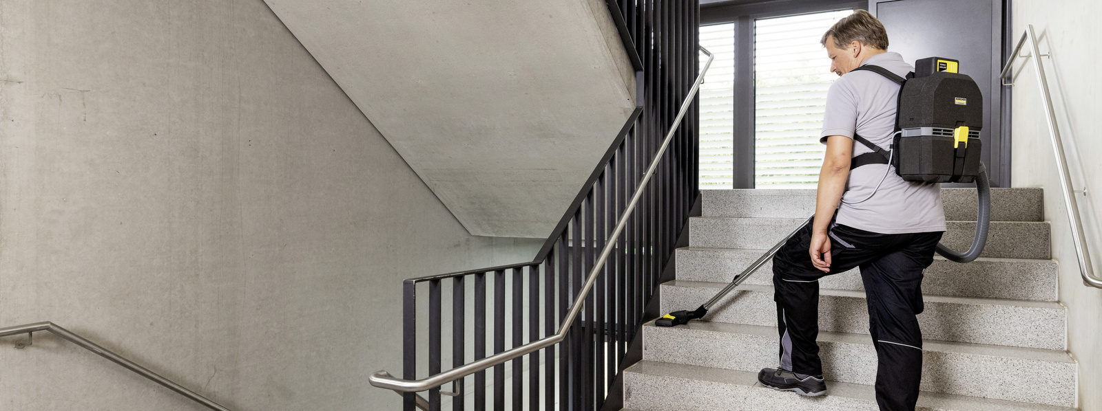 Cleaning stairwell A person is vacuuming the stairs in the stairwell with a Kärcher backpack vacuum cleaner
