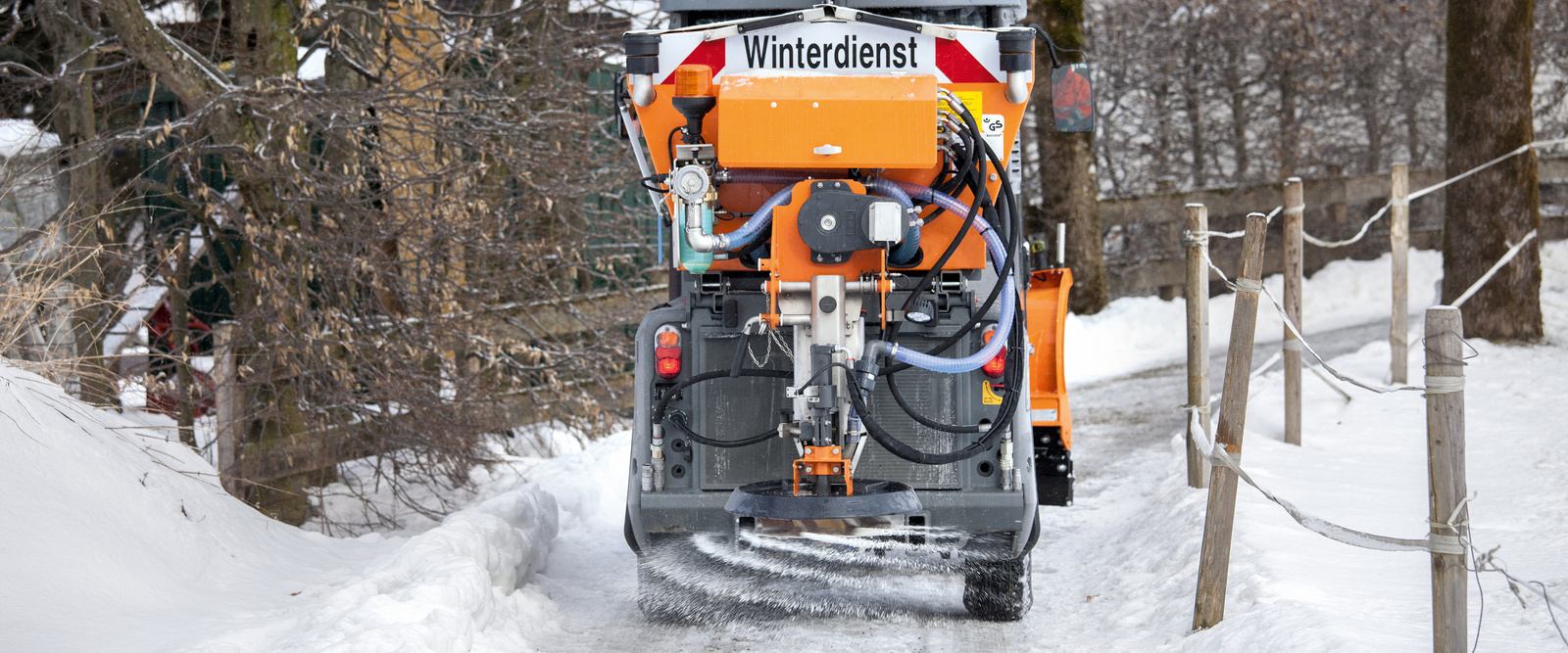 Streufahrzeug im Winter Winterdienst streut einen eingeschneiten Weg