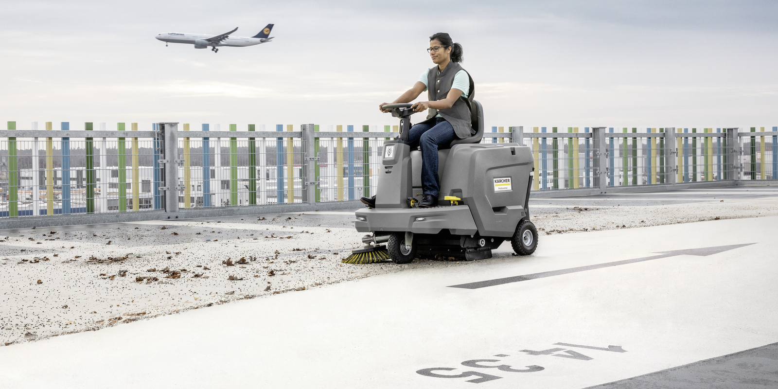 Ride-on sweeper in use A person sitting on a Kärcher ride-on sweeper