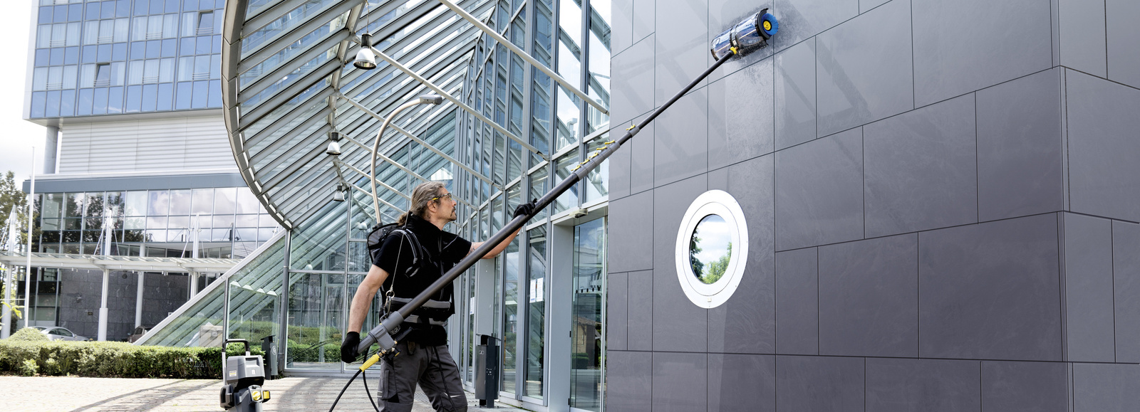 Facade cleaning A person cleaning the facade of a hotel with a high-pressure cleaner