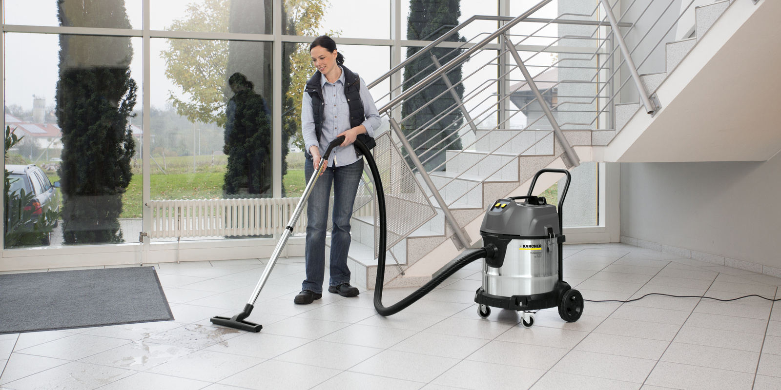 Nass- /Trockensauger im Einsatz Eine Person reinigt den Fließenboden mit dem Nass- /Trockensauger von Kärcher