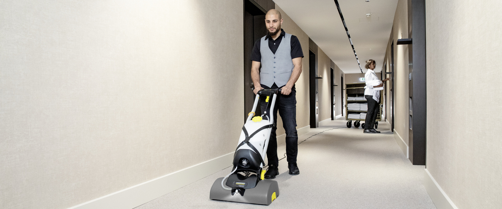 Teppichreinigungsautomat Eine Person reinigt mit einem Teppichreinigungsautomat den Gang eines Hotels