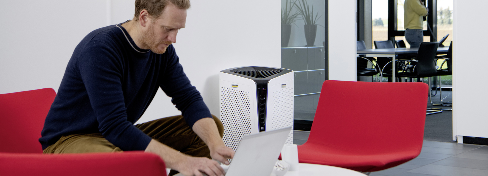 Air purifier A person sits with a laptop next to an air purifier