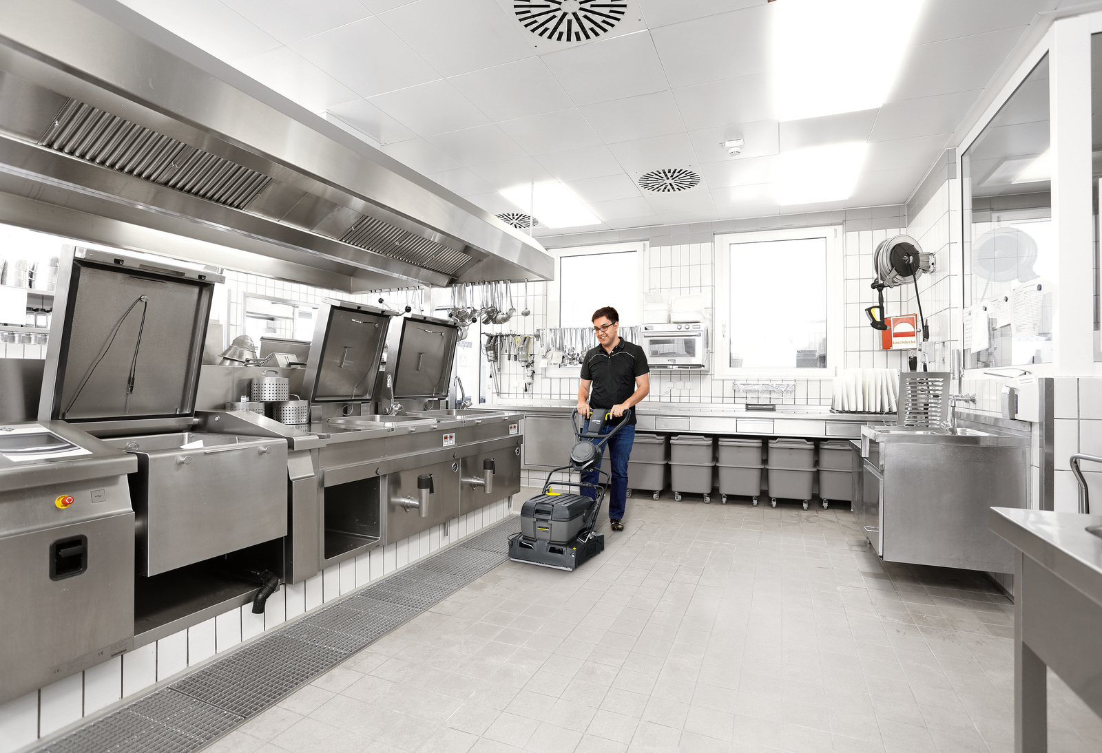 Surface cleaner in use A person cleans the floor of a commercial kitchen with a surface cleaner