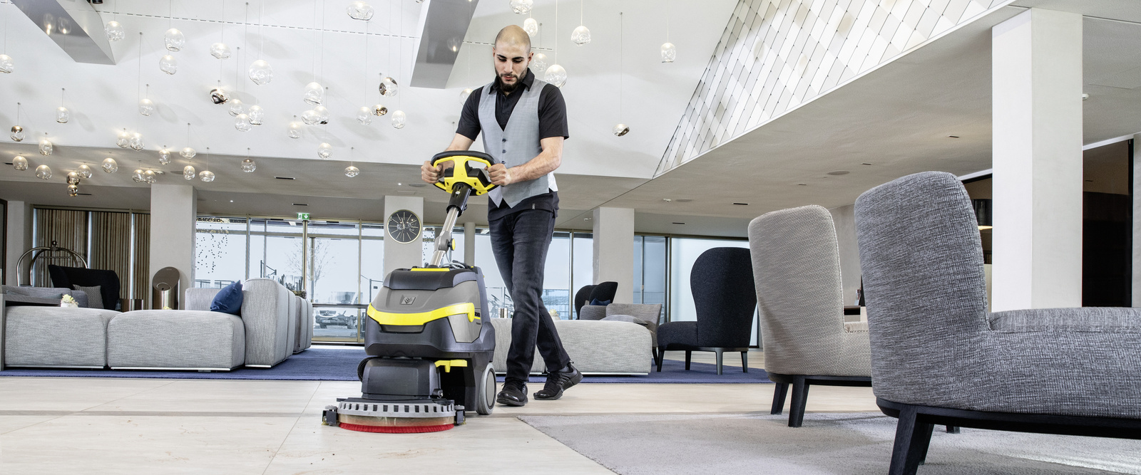 Bodenreinigung mit der Scheuersaugmaschine Eine Person bedient eine Scheuersaugmaschine von Kärcher