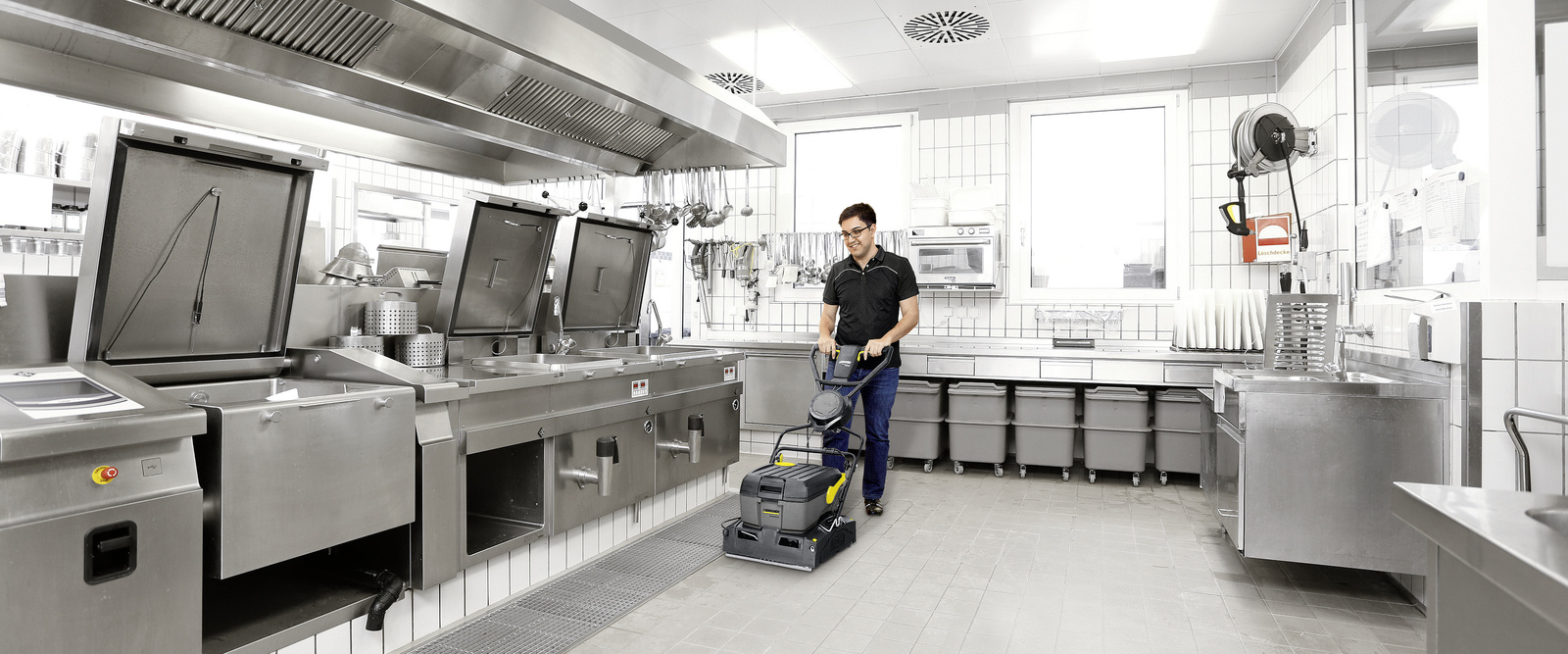 Flächenreiniger Eine Person säubert mit einem Flächenreiniger den Boden einer Grossküche