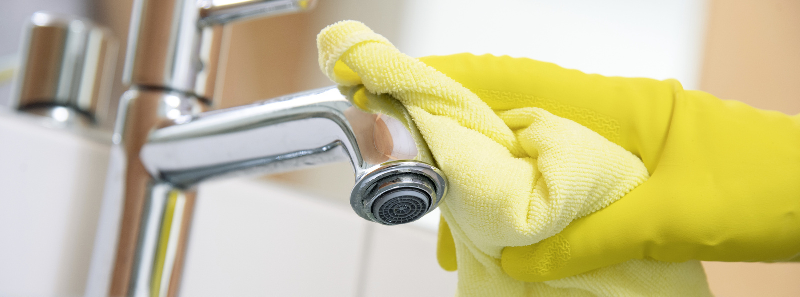 Cleaning in the sanitary area A sink including tap being cleaned with a microfiber cloth