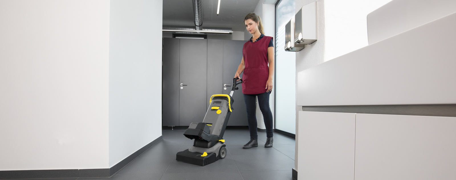 Sanitärreinigung Eine Person reinigt den Fußboden im Toilettenbereich