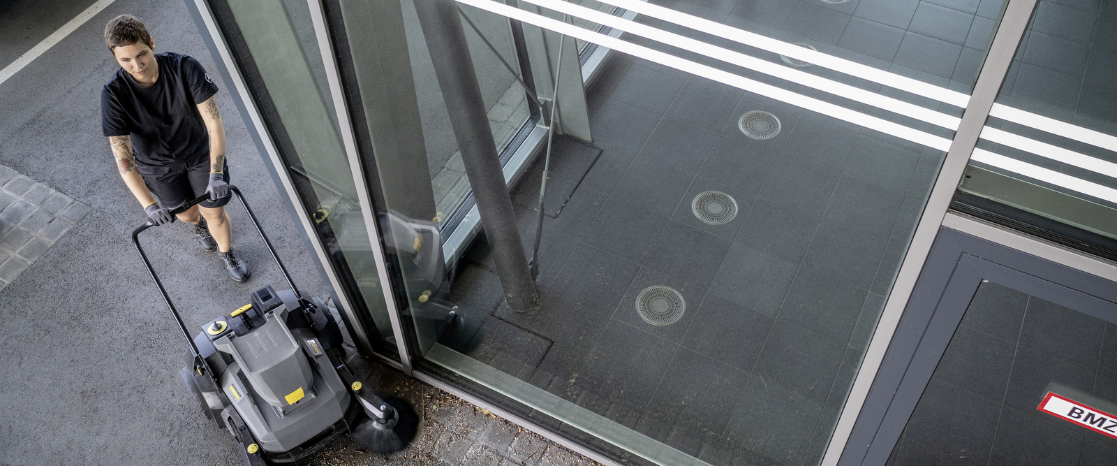 Asphaltreinigung mit der Kehrmaschine Eine Person reinigt den Außenbereich mit der Kehrmaschine von Kärcher