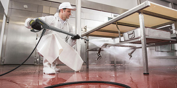 Quieter Operation A worker uses an electric pressure washer in a commercial kitchen