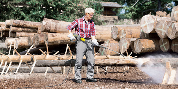 Cordless Convenience A worker strips bark from downed trees using a battery powered pressure washer