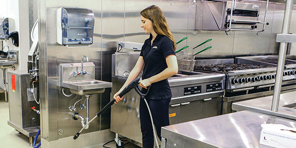 Quiet Operation A worker uses a battery powered pressure washer in a professional kitchen