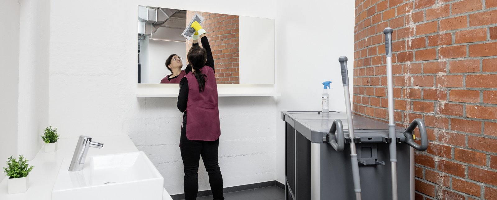 Cleaning in the sanitary area A person cleaning the mirror in the toilet area
