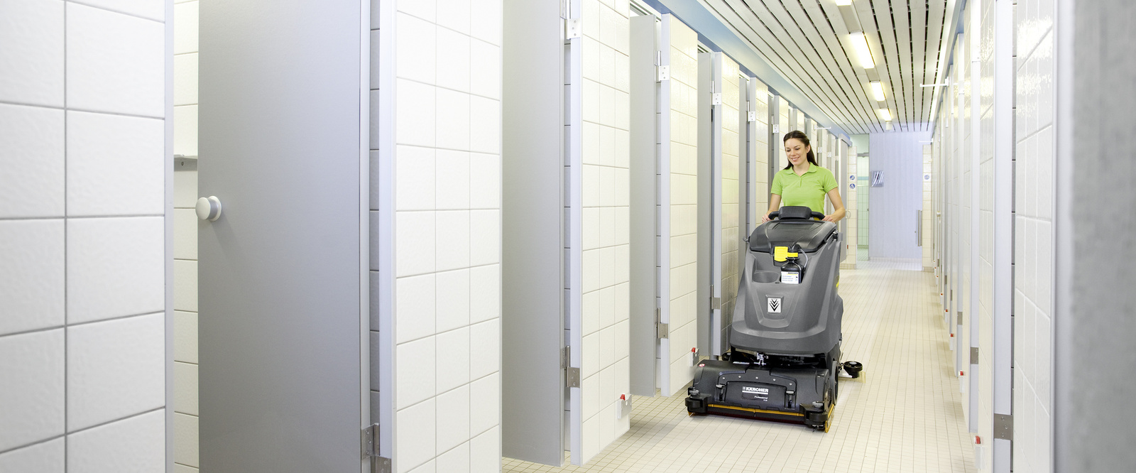 Scrubber dryer in use A person cleaning the tiled floor with a Kärcher scrubber dryer