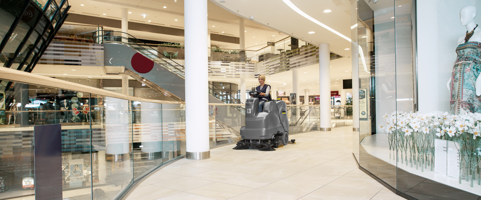 Cleaning a shopping center with a sweeper A person sitting on a sweeper and cleaning a shopping center