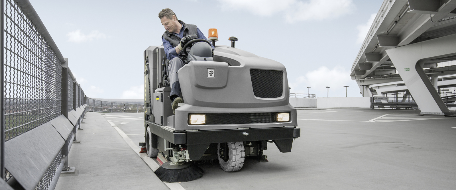 Sweeper in use A person cleaning a parking garage with a ride-on sweeper