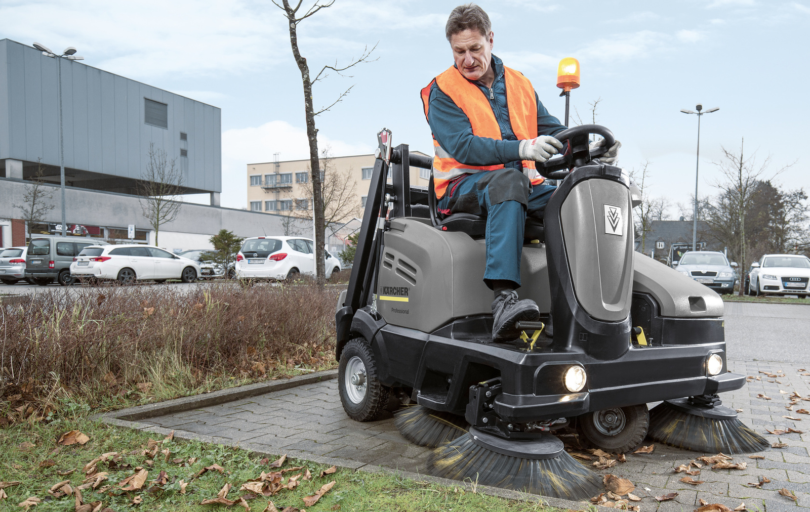 Outdoor surface cleaning A person cleaning a parking lot with a sweeper