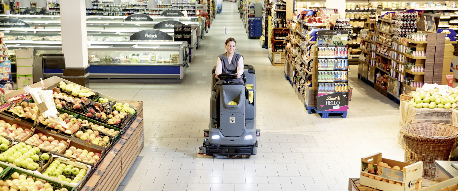 Cleaning a supermarket A person sitting on a scrubber dryer cleaning a grocery store