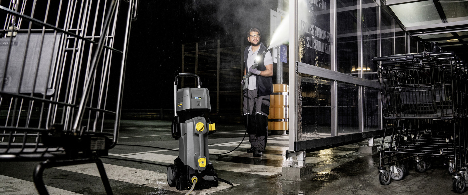 Cleaning shopping carts with a hot water high-pressure cleaner A person cleaning dirty shopping carts with a hot water high-pressure cleaner from Kärcher