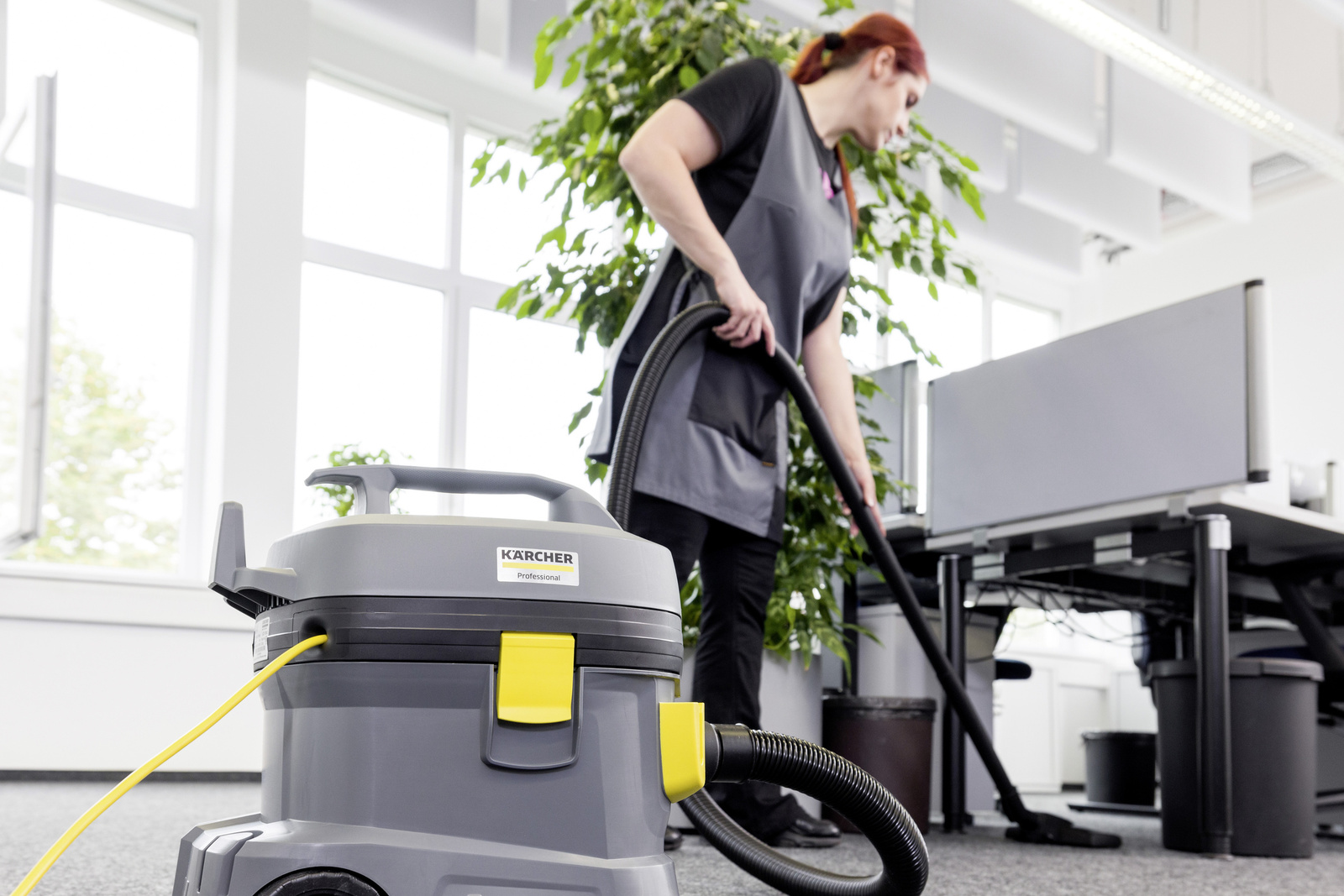 Office cleaning A person cleaning an office room with a dry vacuum cleaner