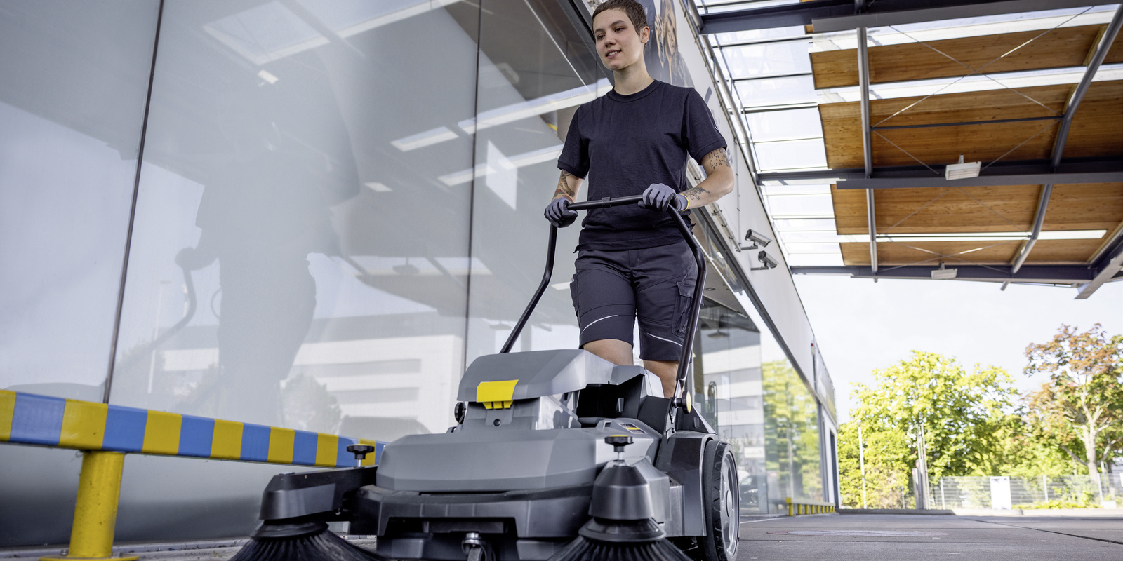 Cleaning with a sweeper A person cleaning an outdoor area with a Kärcher sweeper