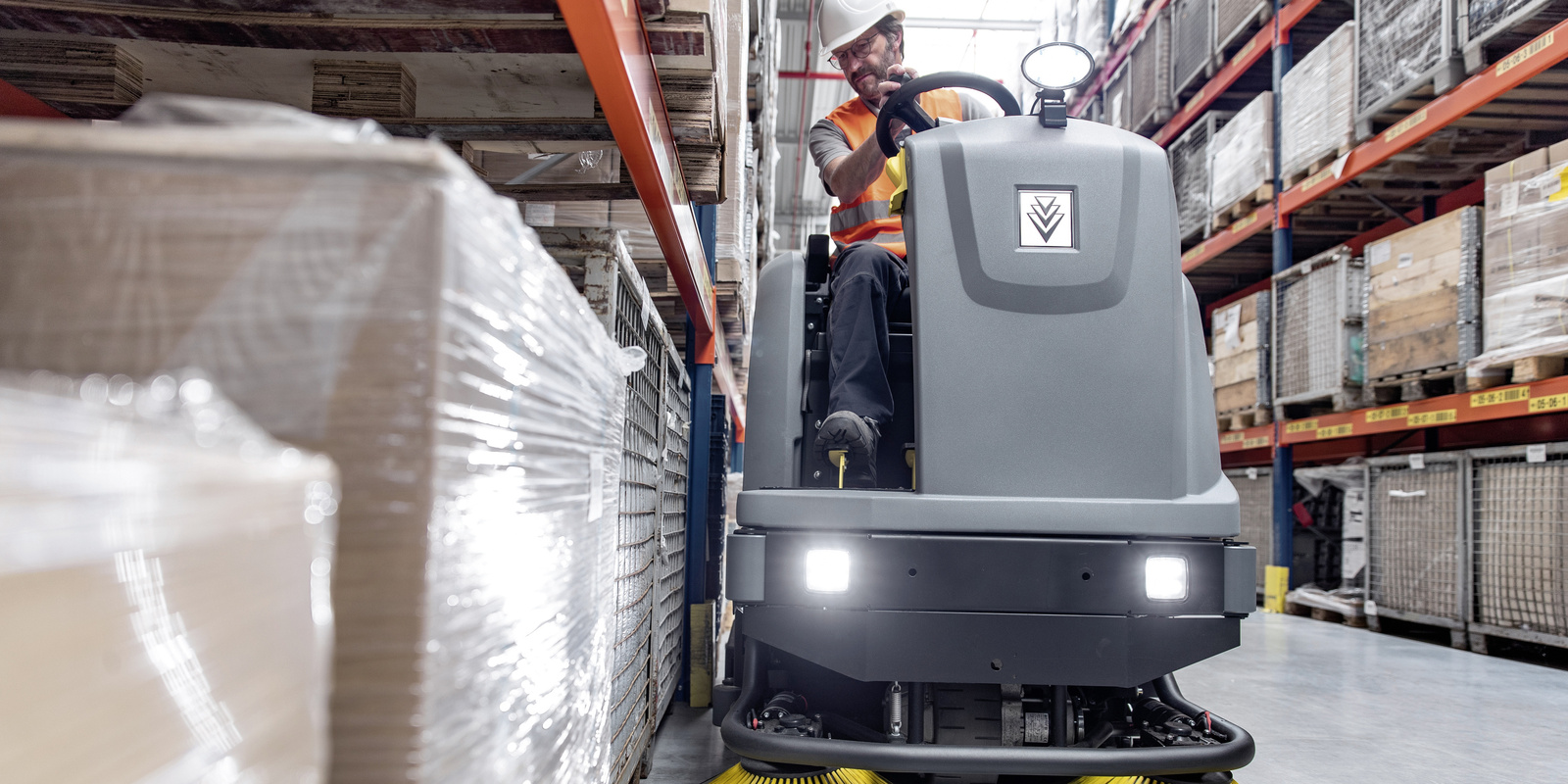Cleaning with a ride-on sweeper A man cleans the floor with a Kärcher ride-on sweeper