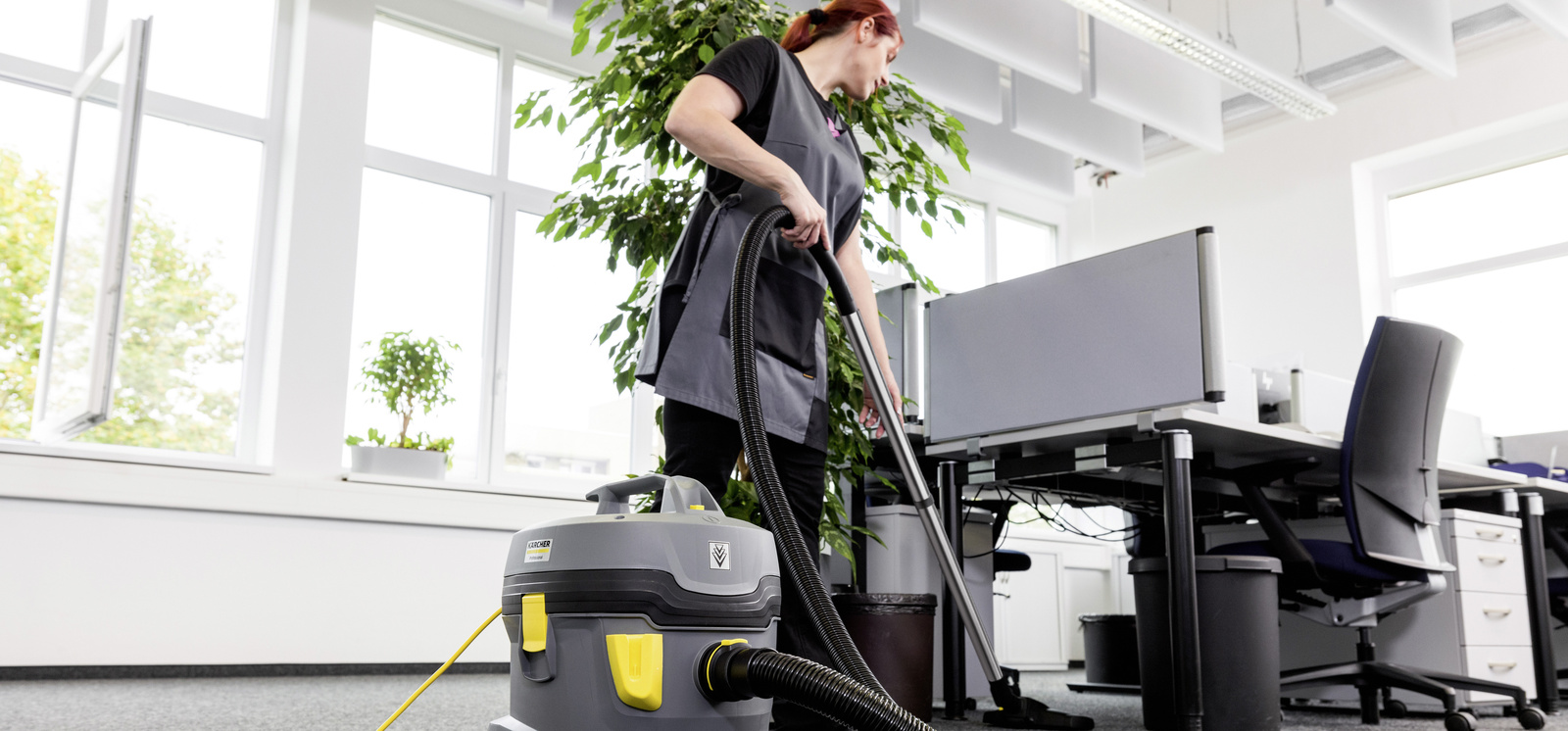 Büroreinigung Eine Person reinigt mit einem Staubsauger von Kärcher einen Büroraum