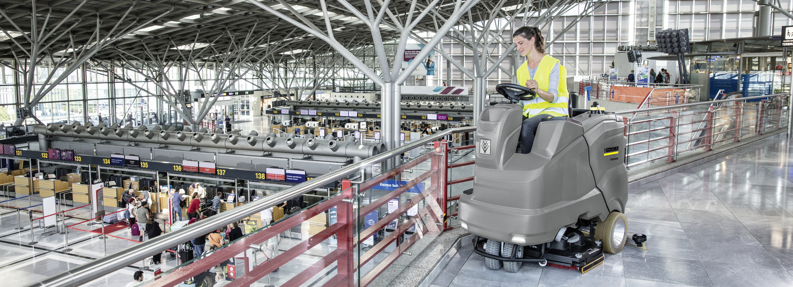 Ride-on scrubber dryer A person cleans the airport area with a ride-on scrubber-dryer from Kärcher