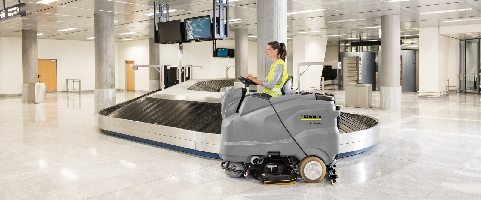 Ride-on scrubber dryer A person sits on a Kärcher ride-on scrubber-dryer and cleans a floor surface