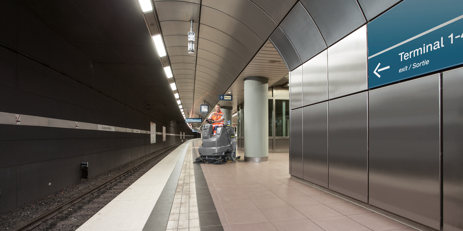 Ride-on sweeper in use A person sits on a ride-on sweeper and cleans a platform