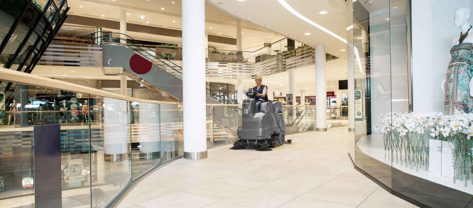 Cleaning shopping centres A person is cleaning a shopping area with a ride-on scrubber dryer
