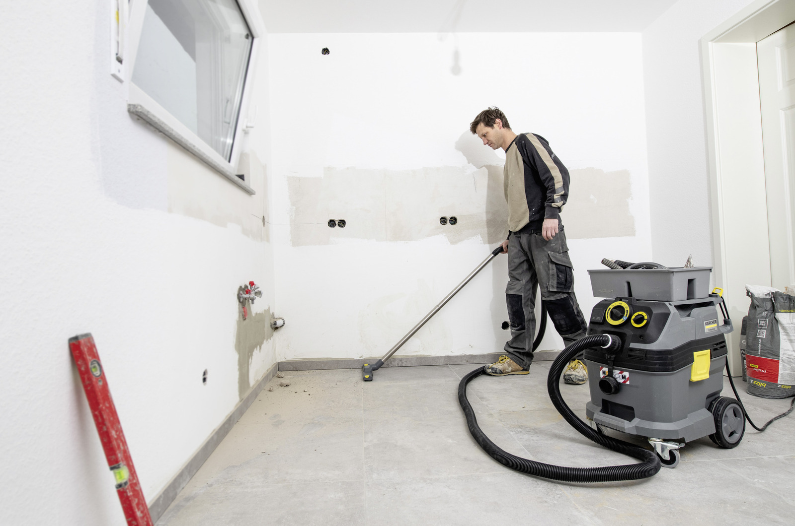 eine Person reinigt den Rohbau-Fußboden mit einem Kärcher Nass-/Trockensauger