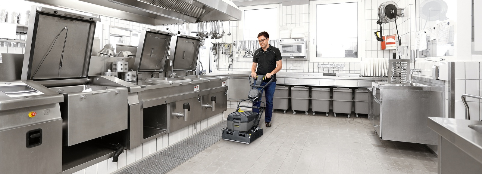 Scrubber dryer in the kitchen A person is cleaning the floor of a hospital kitchen using a scrubber dryer