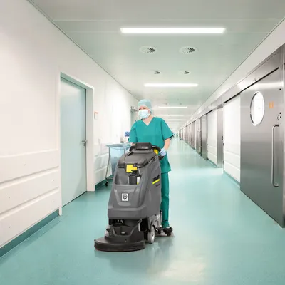 Environmental services professional operating floor-care equipment in a healthcare corridor