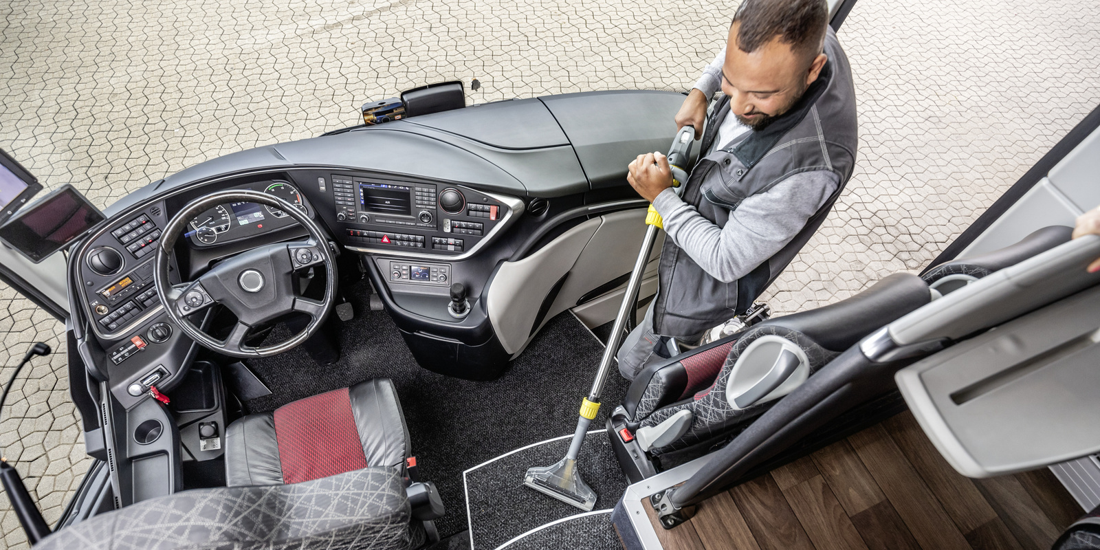 Cleaning of buses A person cleaning the entrance area of a bus with a mini scrubber dryer