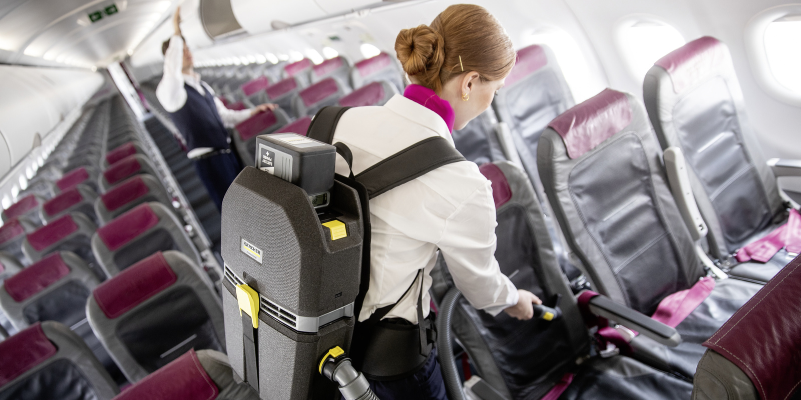 Backpack vacuum cleaner in use A person cleaning the seating of an airplane with a backpack vacuum cleaner