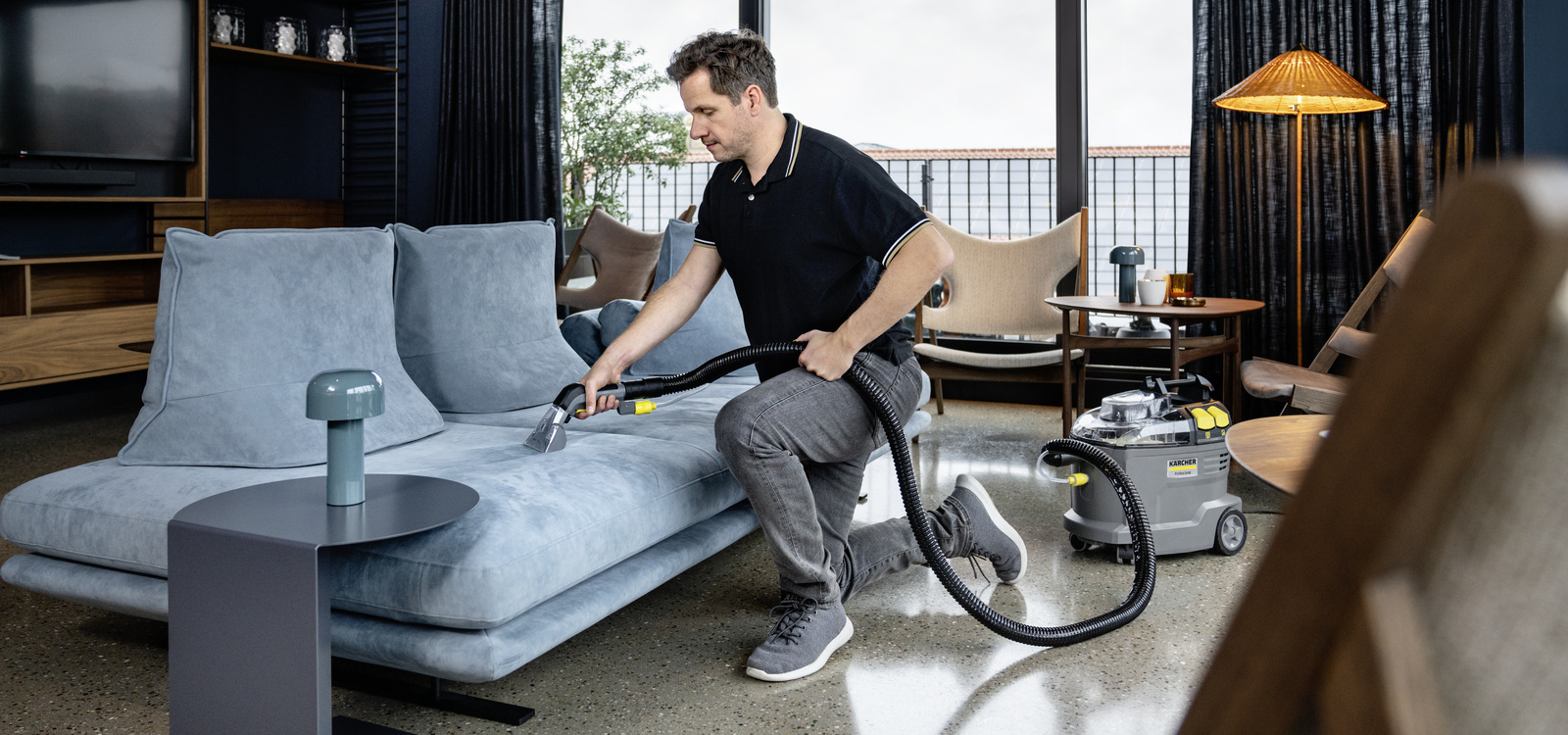 Spray extraction device in use A person cleaning the sofa with a Kärcher spray extraction device