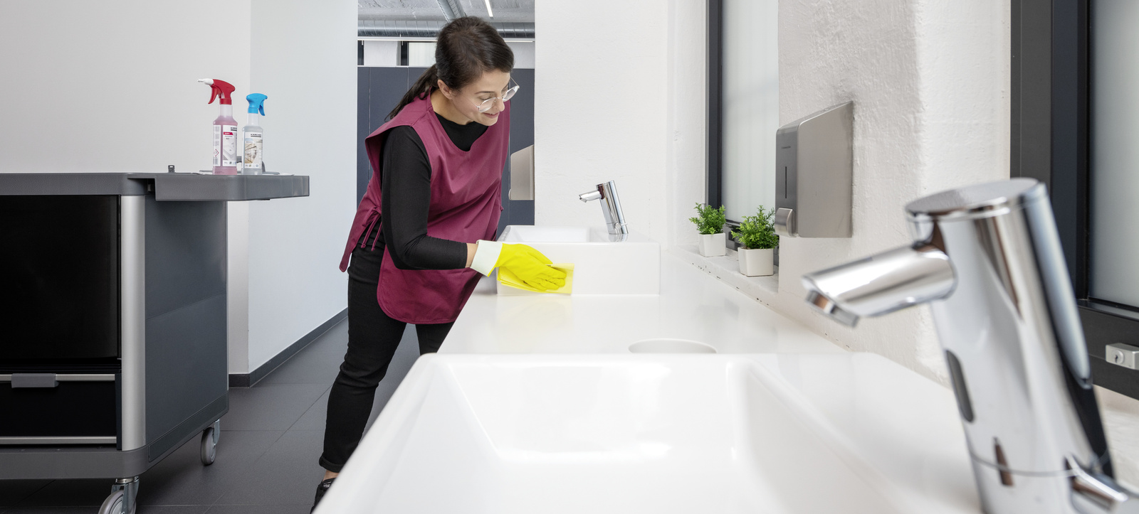 Manual cleaning of sinks A person cleaning a sink with a microfiber cloth