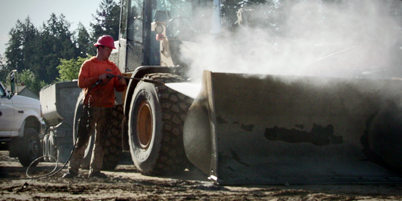 Large and Remote Areas A worker cleans construction equipment on a jobsite