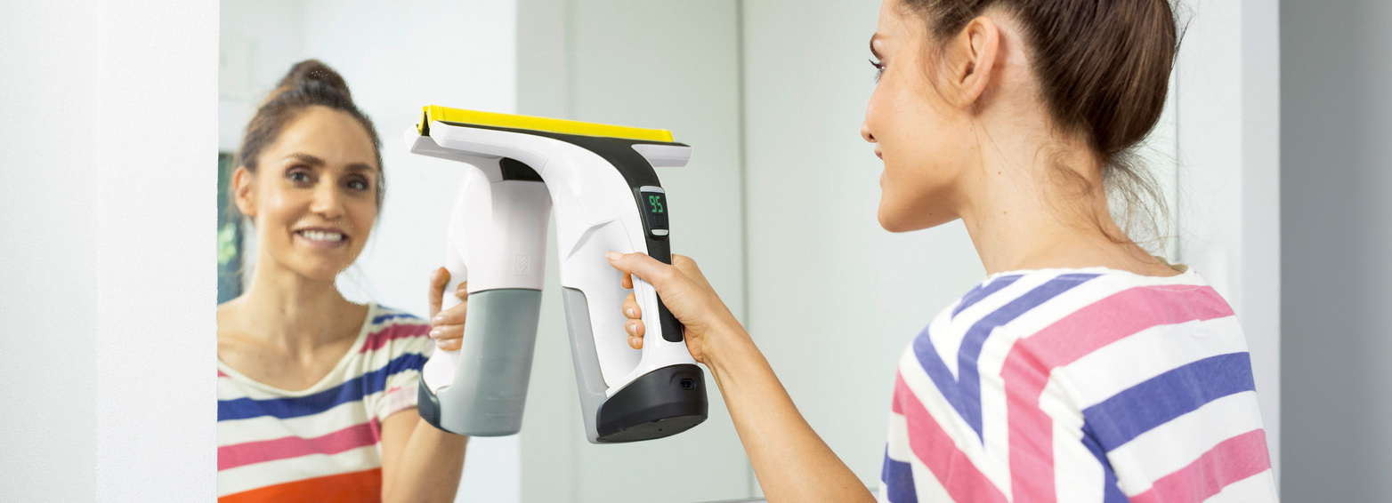 Nettoyage des miroirs Femme nettoyant un miroir avec l'aspirateur nettoyeur de vitres Kärcher