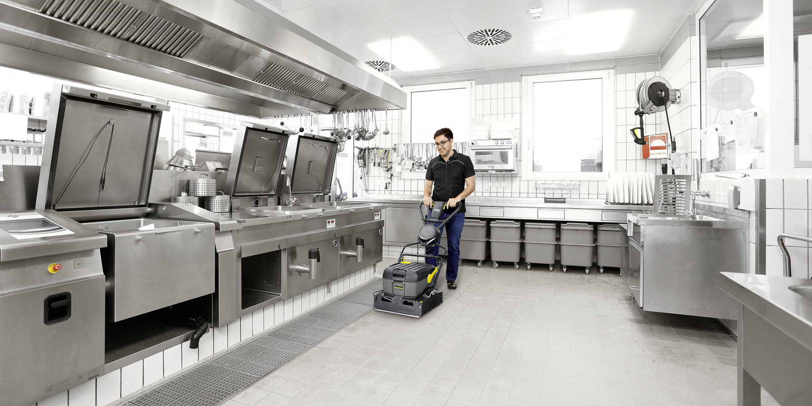 The scrubber dryer in action A person cleaning the kitchen floor with a Kärcher scrubber dryer