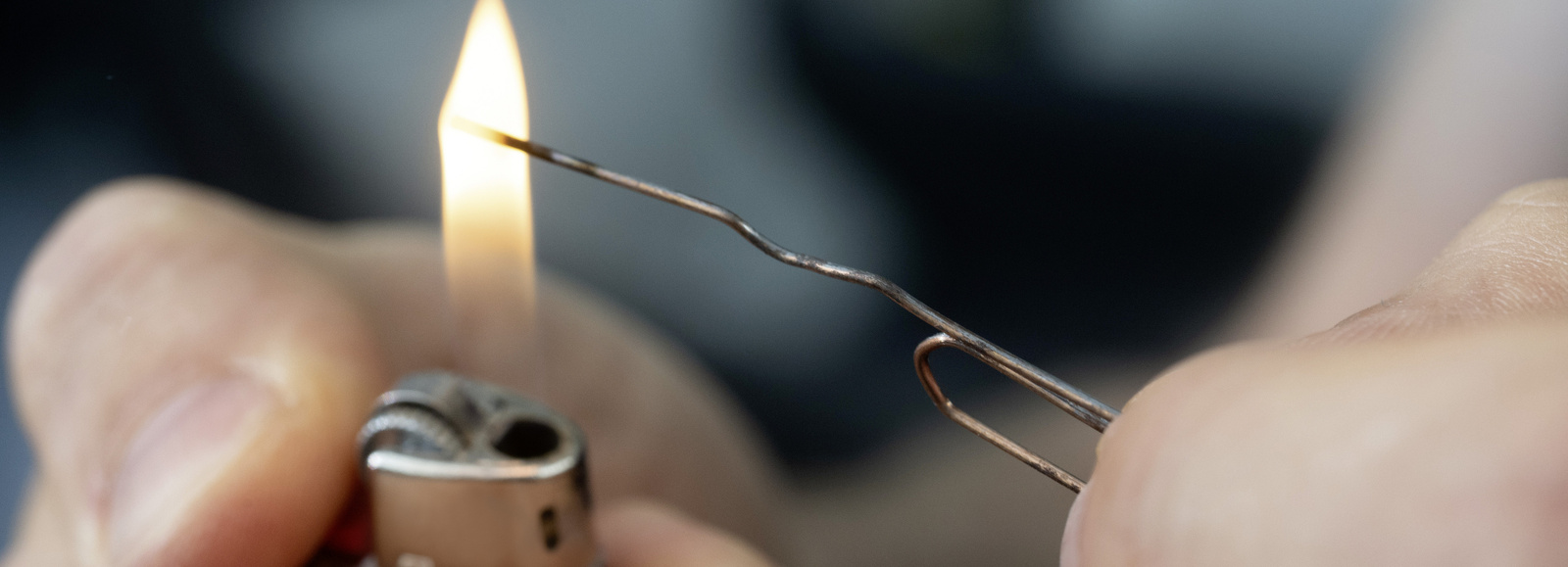 Bent paperclip A bent paperclip is being heated with a lighter.