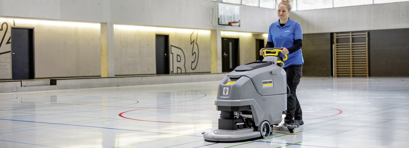 Wet cleaning with a disc brush A woman cleaning the floor of a gym with a disc brush model.