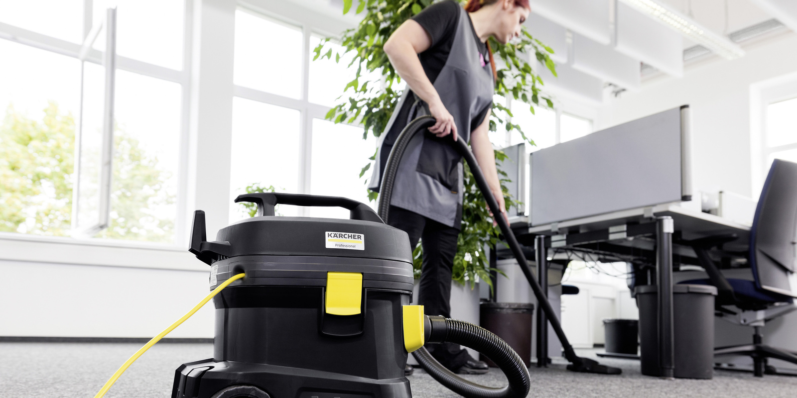 Vacuum cleaner in use A woman cleaning an office with a vacuum cleaner